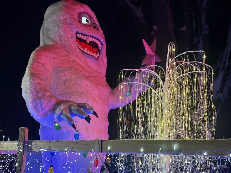 Char de la parade de Noël : un grand monstre des neiges blanc tenant une étoile, saule de lumières et guirlandes bleues
