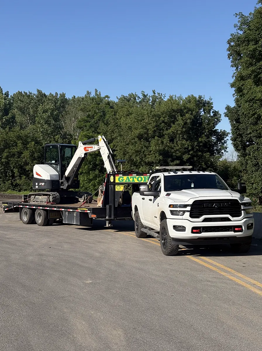 Mini-pelle Bobcat E42 de l'Entreprise SME chargée sur le fardier à col de cygne, attelée à la camionnette RAM, prête à partir
