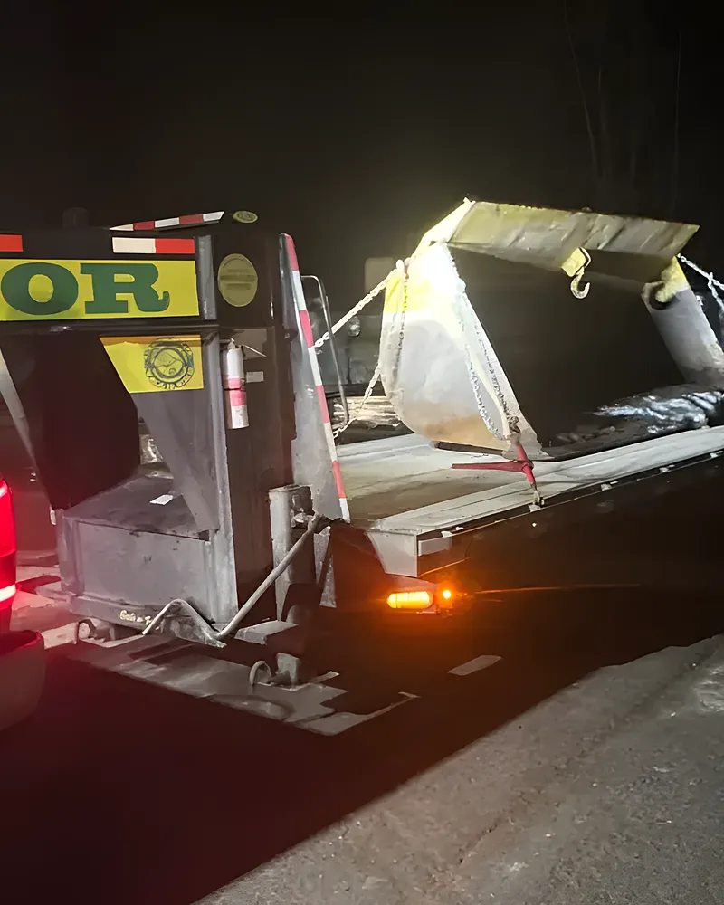 Fardier de l'Entreprise SME de nuit, feux rouges allumés, charge bâchée
